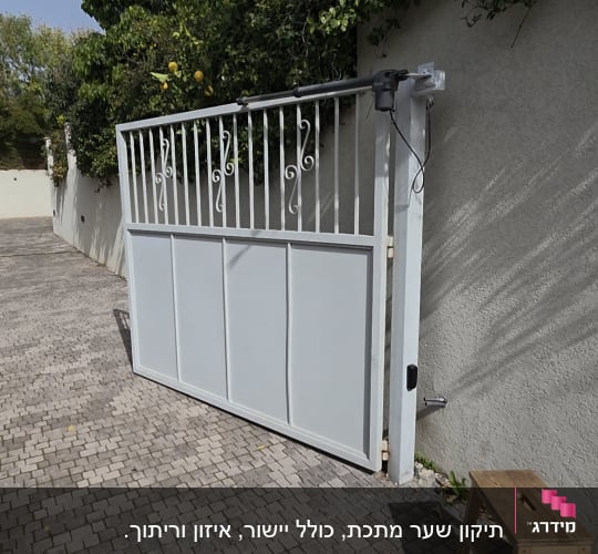 שער מתכת לבן בחניה עם צמחייה מסביב